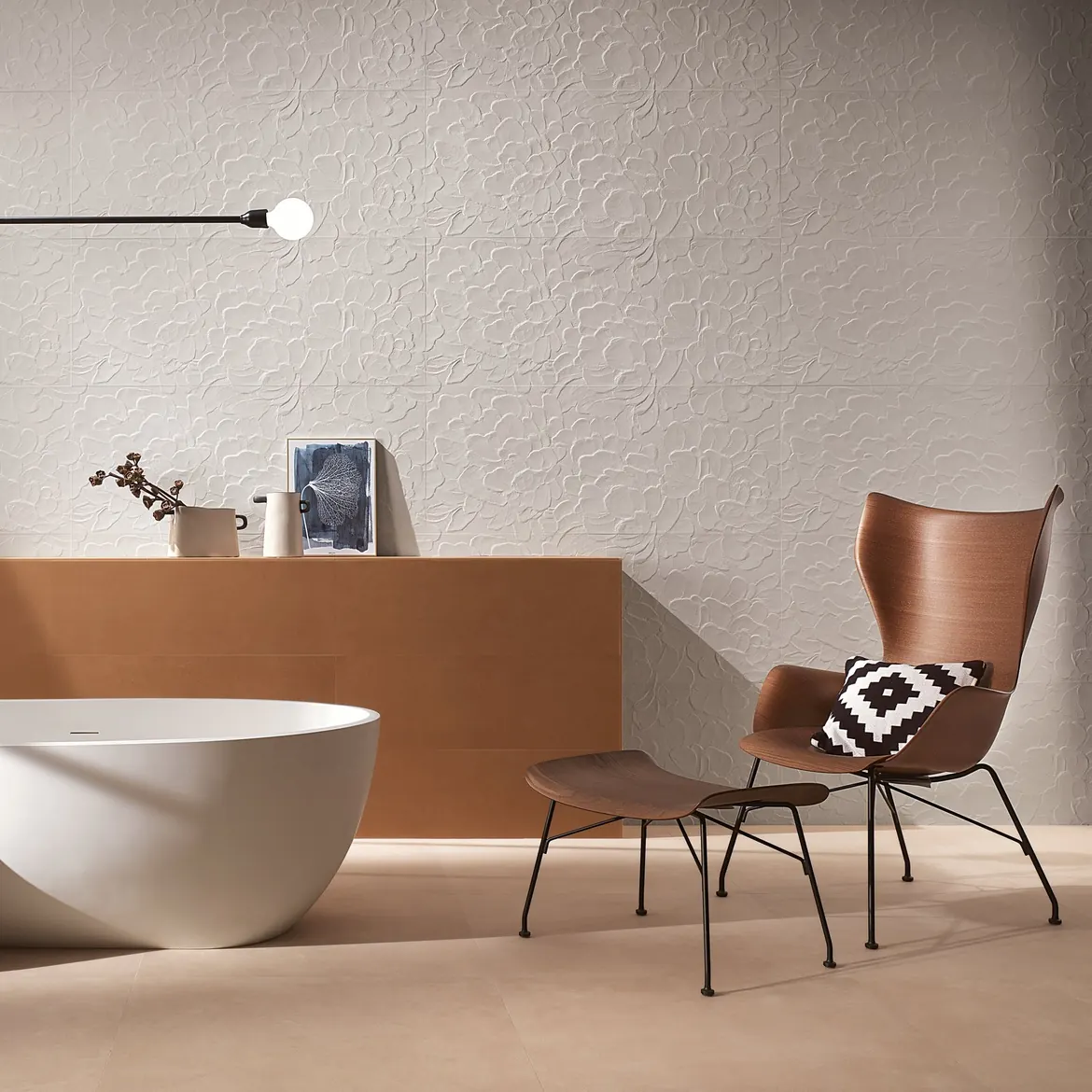 Salle de bain aux tons sable, mur en relief, baignoire îlot et fauteuil en bois